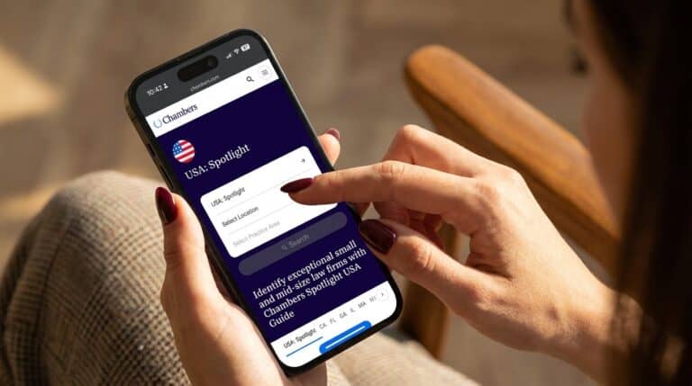 Woman with manicured nails browsing the Chambers and Partners lawyer directory on her phone